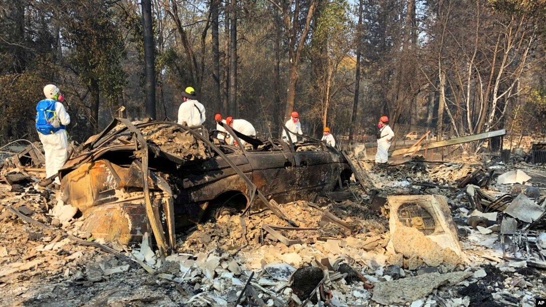 Volunteer members of an El Dorado County search and rescue team search the ruins of a home and vehicle, looking for human remains, in Paradise, Calif., Nov. 18, 2018, following a Northern California wildfire.