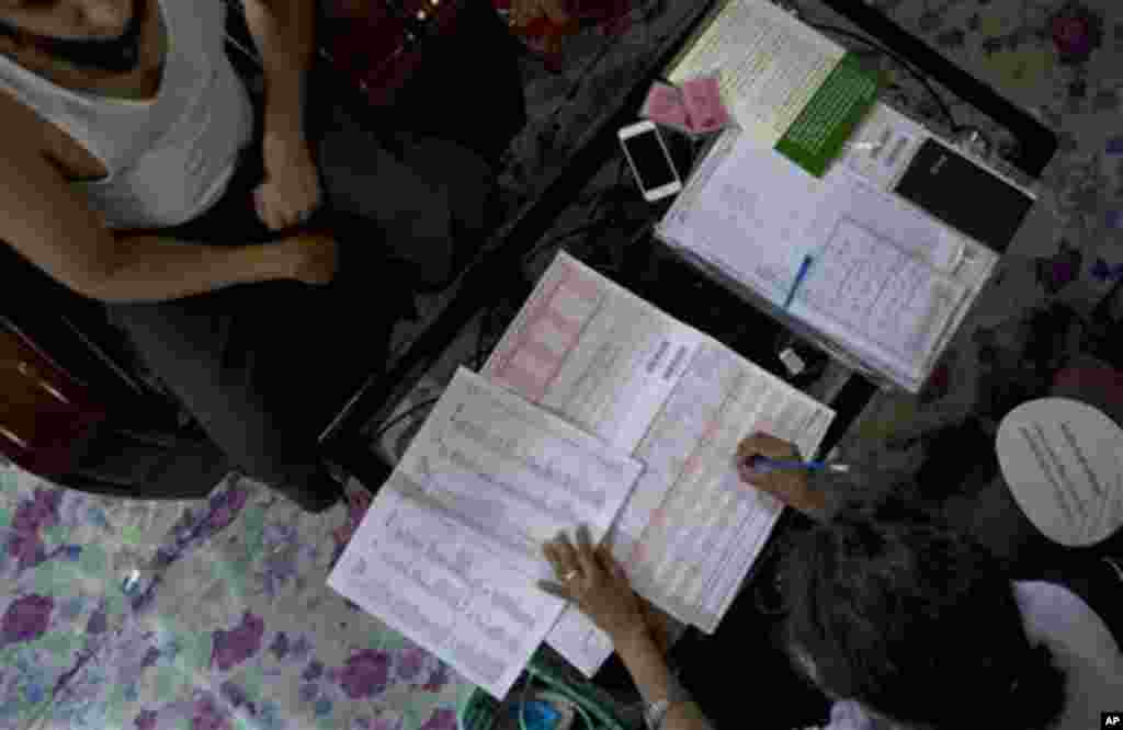 A Myanmar census enumerator, right, collects information to answer a long, complicated questionnaire form from a Muslim family in Yangon, Myanmar, Sunday, March 30, 2014. Enumerators fanned out across Myanmar on Sunday for a census that has been widely cr