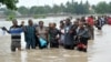 Foto ilustrasi menjukkan sejumlah warga menyeberang jalan yang tergenang banjir di Dar es Salaam, Tanzania, pada 21 Desember 2011. (Foto: AP)