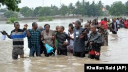 Foto ilustrasi menjukkan sejumlah warga menyeberang jalan yang tergenang banjir di Dar es Salaam, Tanzania, pada 21 Desember 2011. (Foto: AP)