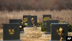 FILE - The gravestones under which unidentified remains of 41 people retrieved from the river since 2017, are seen at the cemetery in Bijeljina, eastern Bosnia, Sunday, February 4, 2024.