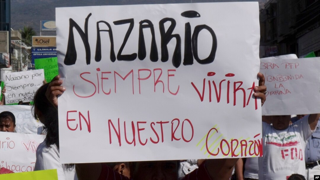 Seorang pria membawa poster bertuliskan "Nazario akan terus hidup dalam hati kami", mengacu pada gembong narkoba Nazario Moreno Gonzalez, dalam demonstrasi di Apatzingan, Meksiko, 2010.