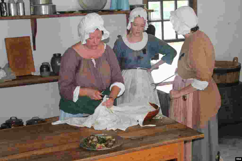 Women cook in a kitchen building in Colonial Williamsburg, a time when a lady never showed her elbow, no matter how hot it got. 