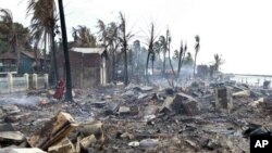 A Buddhist monk stands in the debris of burned houses still smoldering in Sittwe, Burma, Monday, June 11, 2012. 