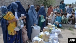 FILE - Afghan women receive food donations as part of the World Food Program (WFP) for displaced people, during the Islamic holy month of Ramadan in Jalalabad on Apr. 20, 2021.