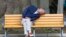 A man takes a nap on a bench at a park in Tokyo, Japan.