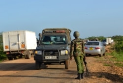 A Kenyan police officer observes motor vehicle traffic near the scene where armed assailants killed three people and injured two others in Nyongoro area of Lamu County, Kenya, Jan. 2, 2020.