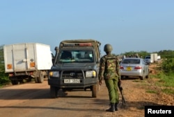 FILE - A Kenyan police officer observes motor vehicle traffic near the scene where armed assailants killed three people and injured two others in Nyongoro area of Lamu County, Kenya, Jan. 2, 2020.