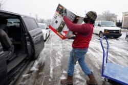 Lowes' employee Jalend Washington carries a kerosene heater to a customer's van, Feb. 18, 2021, in Madison, Miss.