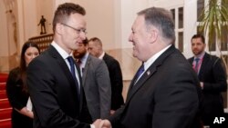 Menlu AS Mike Pompeo (kanan) berjabat tangan dengan Menteri Luar Negeri dan Perdagangan Hongaria, Peter Szijjarto di Budapest, Senin (11/2). 