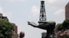 Venezuela: Un hombre camina junto a una escultura frente a un edificio de la compañía petrolera estatal de Venezuela PDVSA en Caracas, Venezuela. 17 de mayo de 2019. 