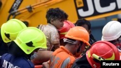 Rescue workers carry Mohammed Bangi, a four-year-old boy, after he was rescued from the remains of a collapsed five-story building in Mahad, in the western state of Maharashtra, India.