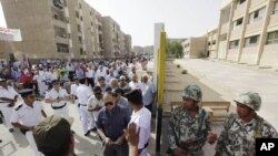 Egyptian army soldiers, right, stand guard as hundreds of Egyptians line up outside a polling station in Cairo, Egypt, May 23, 2012. 