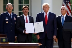Defense Mark Esper holds a document he signed to establish the U.S. Space Command with Gen. John "Jay" Raymond, left, President Donald Trump and Vice President Mike Pence, Aug. 29, 2019, in Washington.