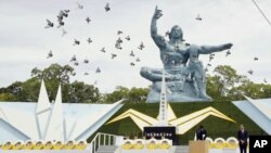 Palomas vuelan alrededor de la Estatua de la Paz durante una ceremonia por el 74to aniversario del ataque con bomba atómica que marcó el final de la Segunda Guerra Mundial, en el Parque de la Paz de Nagasaki, en el sur de Japón, el 9 de agosto de 2019. (Kyodo News via AP)