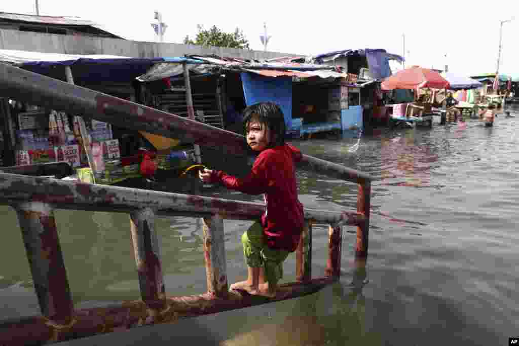 A young girl plays during a tidal flood at Muara Angke Port in Jakarta, Indonesia.