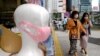 Para pejalan kaki melintas di depan boneka peraga dengan masker wajah di sebuah apotek di Tokyo, 31 Mei 2020. (Foto: AFP)