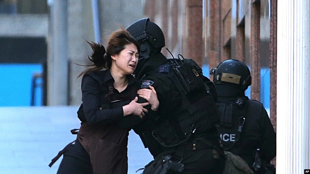 Seorang sandera berlari ke arah polisi setelah melarikan diri dari penyanderaan di kafe di distrik bisnis Martin Place, Sydney, Australia (15/12). (AP/Rob Griffith)