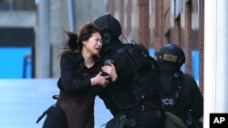 Seorang sandera berlari ke arah polisi setelah melarikan diri dari penyanderaan di kafe di distrik bisnis Martin Place, Sydney, Australia (15/12). (AP/Rob Griffith)