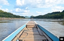 A boat motors down a rocky stretch of the Mekong River in northern Laos in November 2019. (Zsombor Peter/VOA)