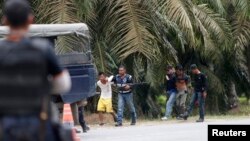 Cảnh sát Malaysia bắt 2 người đang ra khỏi ngôi làng, gần khu vực Kampung Tanduo, nơi binh sĩ Malaysia đột kích vào trại của nhóm người Philippines võ trang 