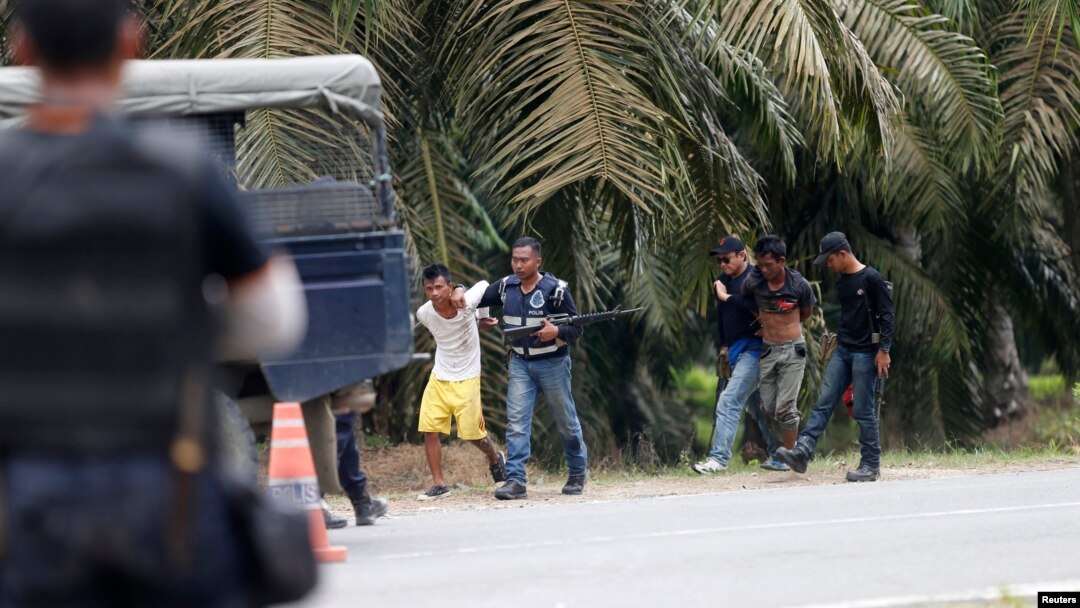 Polisi Malaysia menahan dua orang pria yang keluar dari desa Tanjung Labian, dekat daerah perkebunan di Sabah (6/3). 