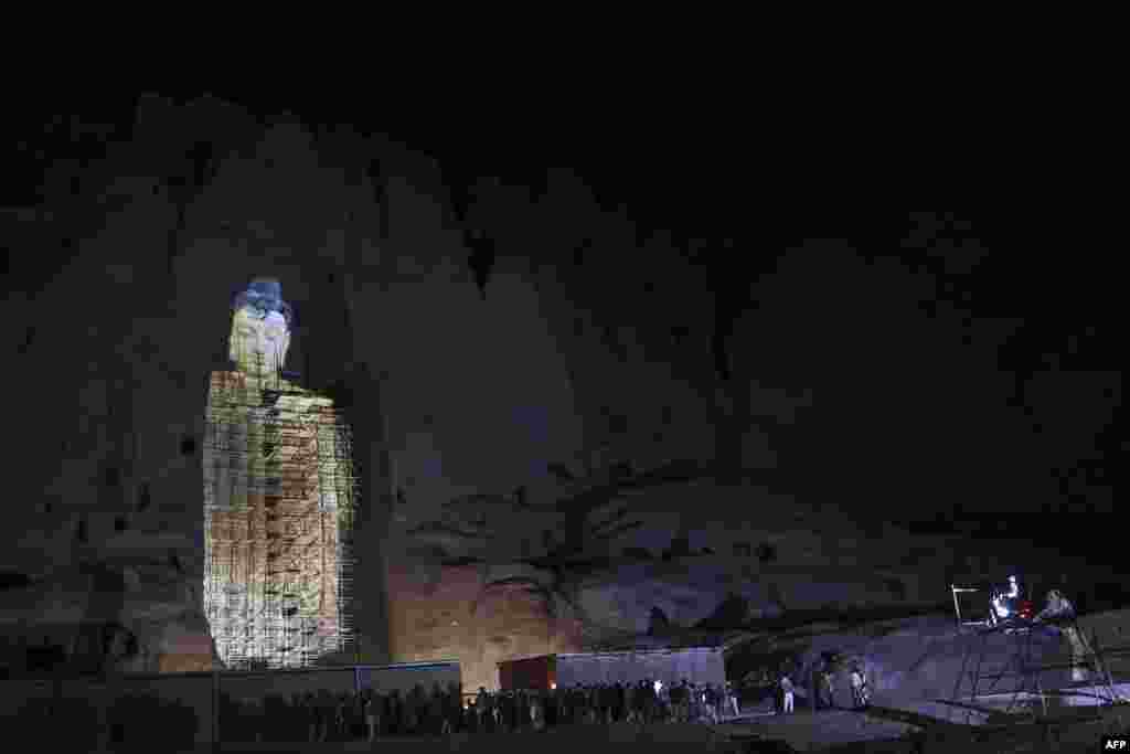 People watch a three-dimensional projection of the 56 meters-high Salsal Buddha at the site where the Buddhas of Bamiyan statues stood before being destroyed by the Taliban in March 2001, in Bamiyan province, Afghanistan.