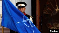 An honor guard raises the NATO flag in front of the Macedonian government in Skopje, February 12, 2019. REUTERS/Ognen Teofilovski