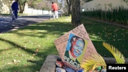 Gardeners clean the lawn as a get well card is placed outside the house of former President of South Africa Nelson Mandela in Houghton, June 10, 2013. 