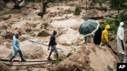 FILE: People cross a raging river in Blantyre, Malawi, Monday, March 13, 2023. An unrelenting Cyclone Freddy battered southern Africa in Malawi and Mozambique, striking the continent for a second time.