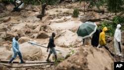 FILE - People cross a raging river in Blantyre, Malawi, Monday, March 13, 2023. 