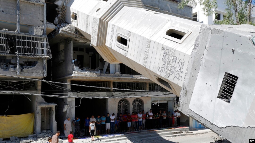 Palestinian Muslim worshipers attend Friday noon prayer beneath the fallen minaret of the al-Susi mosque in Gaza City on Sept. 12, 2014 which was hit by Israeli strikes during the latest round of deadly fighting with Hamas militants. 
