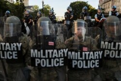 FILE - DC National Guard Military Police officers and federal law enforcement officers stand guard during a protests near the White House, in Washington, June 1, 2020.