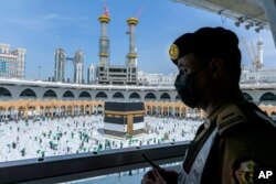 Seorang petugas keamanan Saudi mengamati para jemaah yang tengah menunaikan ibadah haji dengan mengenakan masker dan menjaga jarak sosial di tengah pandemi COVID-19 di Masjid Agung, di Makkah Arab Saudi, 21 Juli 2021. (AP)