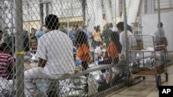 FILE - A photo provided by U.S. Customs and Border Protection shows people taken into custody related to cases of illegal entry into the United States, at a facility in McAllen, Texas, June 17, 2018.