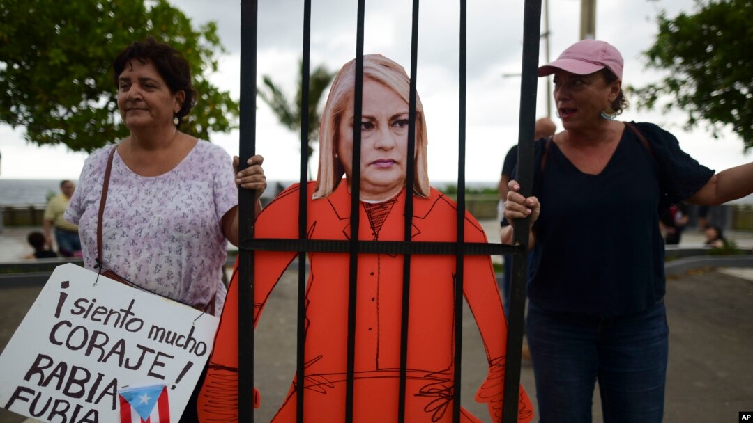 Bajo una fuerte lluvia, los manifestantes se reunieron en la mansión de la gobernadora Wanda Vázquez ondeando banderas, golpeando ollas y exigiendo su renuncia.