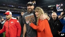 ARCHIVO - El tight end de los Chiefs de Kansas City Travis Kelce camina con Taylor Swift tras el campeonato de la AFC ante los Ravens de Baltimore el domingo 28 de enero de 2024, en Baltimore.