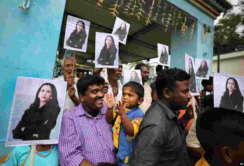 A child reacts as villagers hold placards featuring then U.S. Vice President-elect Kamala Harris, after participating in special prayers ahead of her inauguration, outside a Hindu temple in Thulasendrapuram, south of Chennai, Tamil Nadu state, India.