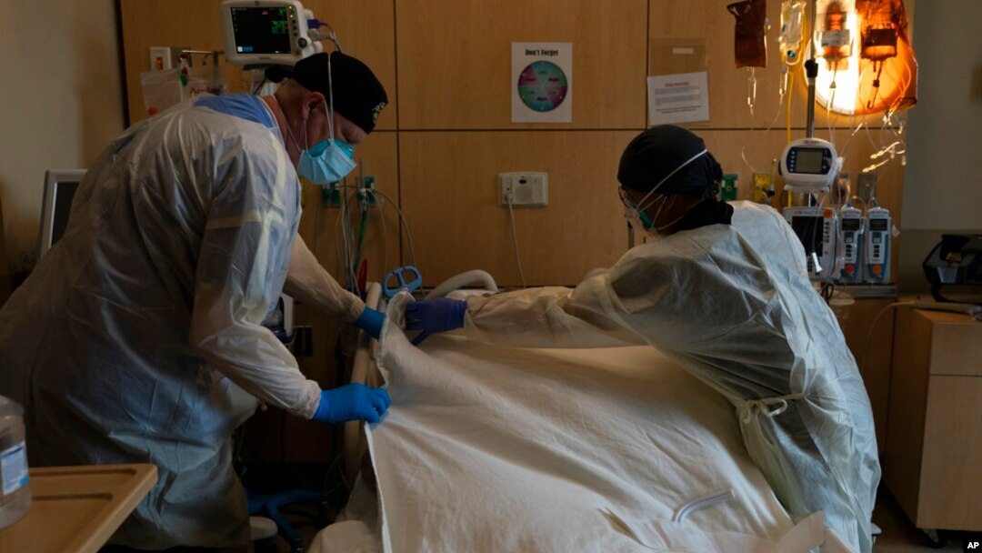 Terapis pernapasan Frans Oudenaar, kiri, dan perawat terdaftar Bryan Hofilena menutupi tubuh pasien COVID-19 dengan selembar kain di Providence Holy Cross Medical Center di Los Angeles, 14 Desember 2021. (Foto: AP)