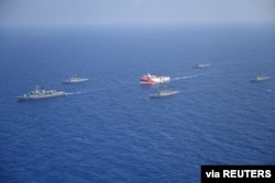 FILE - Turkish seismic research vessel Oruc Reis is escorted by Turkish Navy ships as it sets sail in the Mediterranean Sea, off Antalya, Turkey, Aug. 10, 2020.