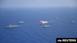 FILE - Turkish seismic research vessel Oruc Reis is escorted by Turkish Navy ships as it sets sail in the Mediterranean Sea, off Antalya, Turkey, Aug. 10, 2020. 