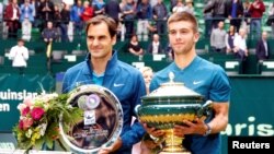Petenis Kroasia, Borna Coric, berpose dengan trofi turnamen bersama dengan juara kedua, Roger Federer asal Swedia, setelah mengalahkan Federer di final Halle Terbuka di Stadion Gerry Weber, Jerman, 24 Juni 2018.