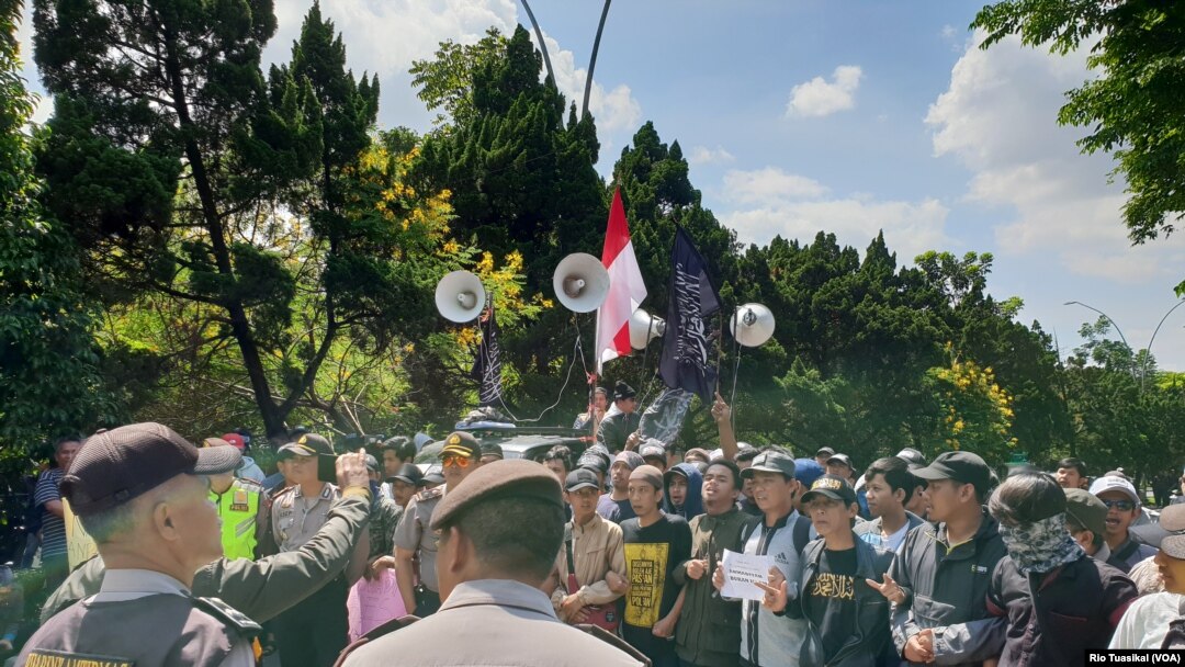 Kelompok orang yang menolak diskusi buku Ahmadiyah berorasi dengan pengawalan ketat kepolisian. (Foto: VOA/Rio Tuasikal)