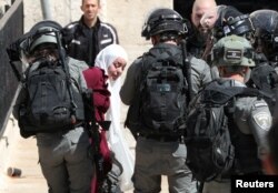 Israeli security force members detain a Palestinian woman during a demonstration held by Palestinians to show their solidarity amid Israel-Gaza fighting, at Damascus Gate just outside Jerusalem's Old City, May 18, 2021.