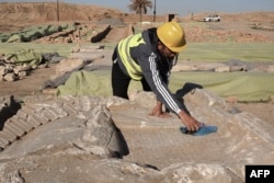 An archaeological expert cleans dirt from an artifact at the archaeological site of Nimrud in Iraq, Jan. 3, 2025.