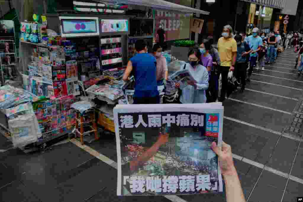 A woman takes a picture of the last edition of Apple Daily as people queue up to buy the newspaper in Hong Kong. Apple Daily was forced to shut down after five editors and executives were arrested under the one-year-old national security law.