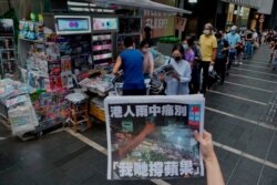 A woman takes a picture of the last edition of Apple Daily as people queue up to buy the newspaper in Hong Kong, June 24, 2021.