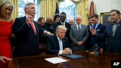 FILE - Religious leaders pray with President Donald Trump after he signed a proclamation for a national day of prayer to occur on Sunday, Sept. 3, 2017, in the Oval Office of the White House in Washington.