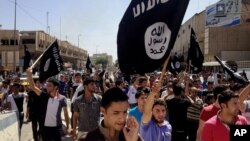 Demonstrators supporting the Islamic State of Iraq and the Levant (ISIL) carry al-Qaida flags in front of the provincial government headquarters, Mosul, June 16, 2014.