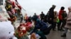 Люди покладають квіти до імпровізованого меморіалу жертвам обстрілу в концертному залі під Москвою, де у п'ятницю, 22 березня загинуло понад 60 і поранено понад 100 осіб.